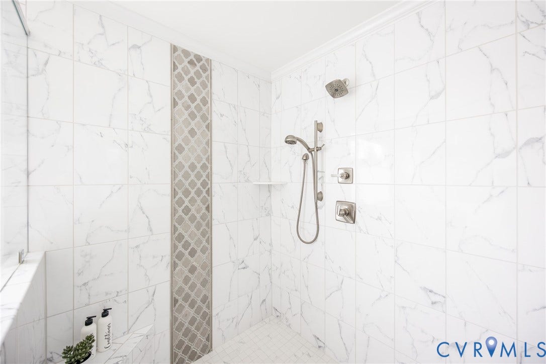 The primary shower is very large and has a tiled seat, dual shower heads and frameless enclosure.