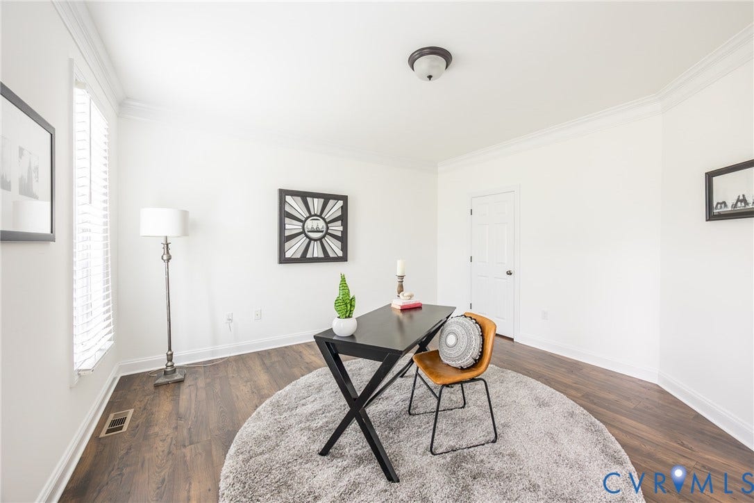 View of the office with windows as well as a door that leads to the drop zone, 1/2 bath and kitchen area.