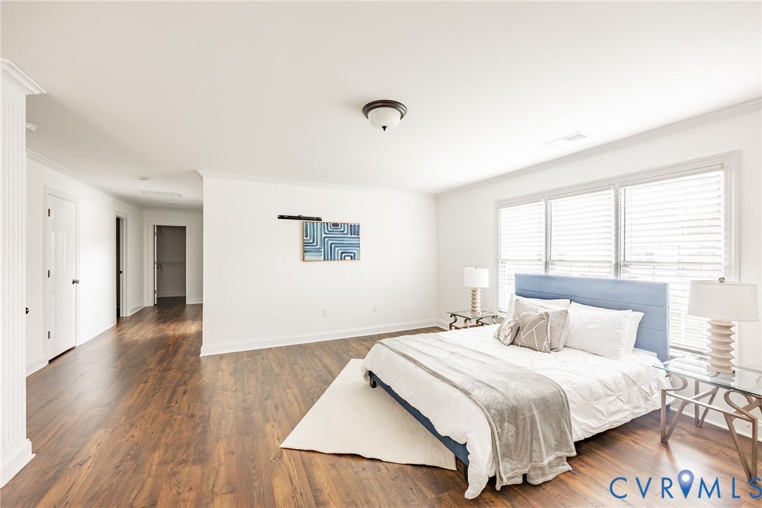 View of the primary bedroom hallway that leads to two walk-in closets as well as the primary bathroom. The hallway has an area that is pre plumbed for a coffee/beverage area.