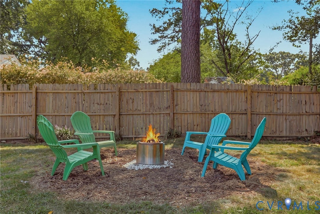 5108 Forest Hill Avenue, Westover Hills Area, Richmond, VA 23225 Private backyard featuring a wood privacy fence, mature trees, and a dedicated fire pit area with white stone accents