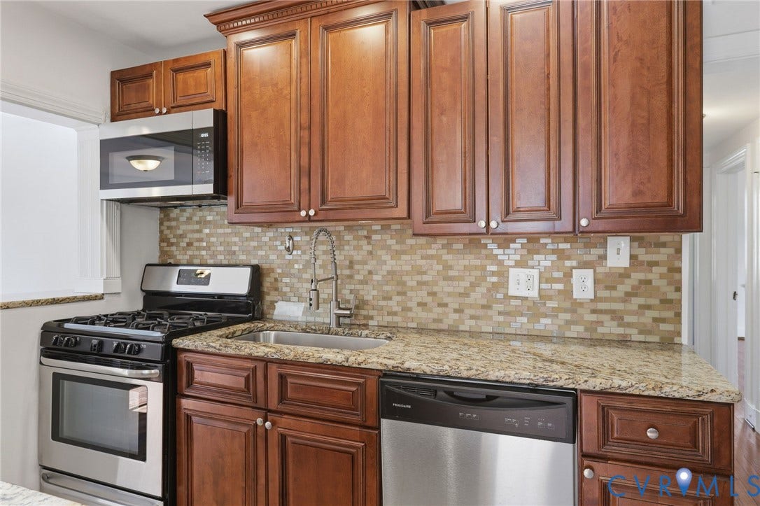 5108 Forest Hill Avenue, Westover Hills Area, Richmond, VA 23225 Wood-finish cabinetry paired with granite countertops, a mosaic tile backsplash, and new stainless steel microwave.