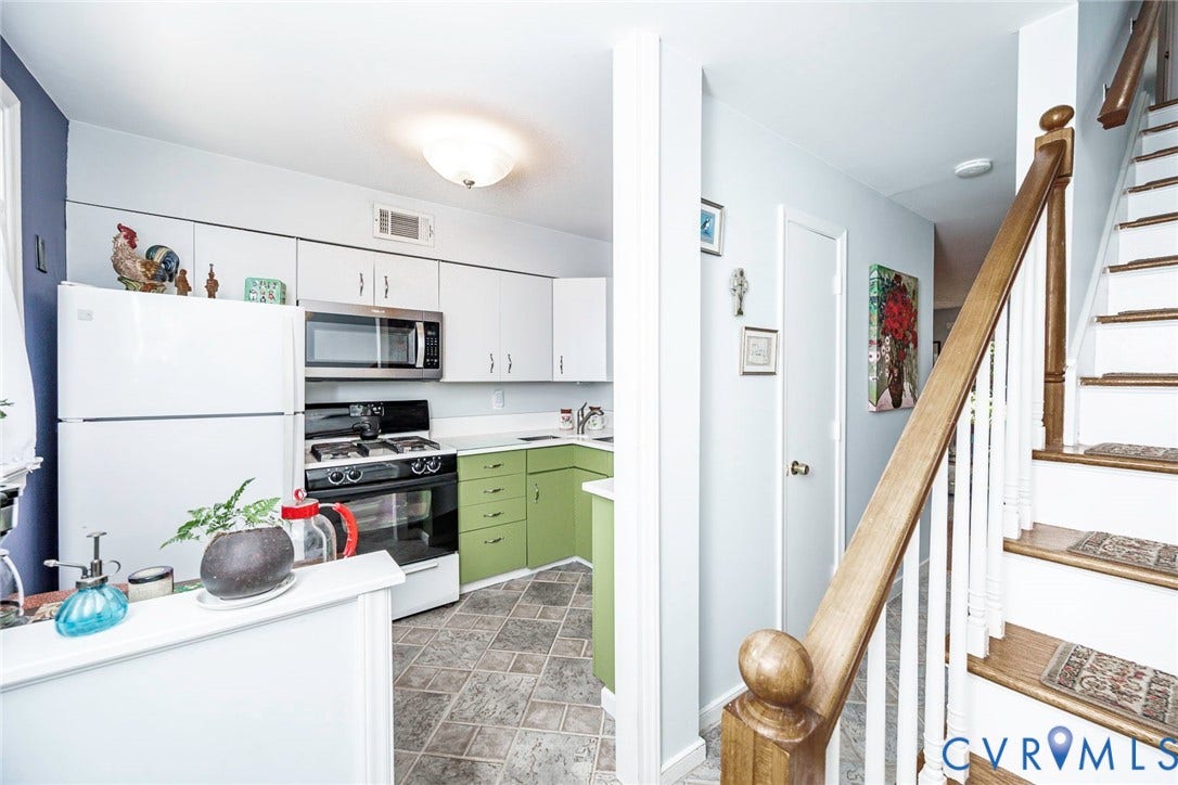 Kitchen featuring light upper cabinetry, green base cabinets, stainless steel microwave, and a gas range