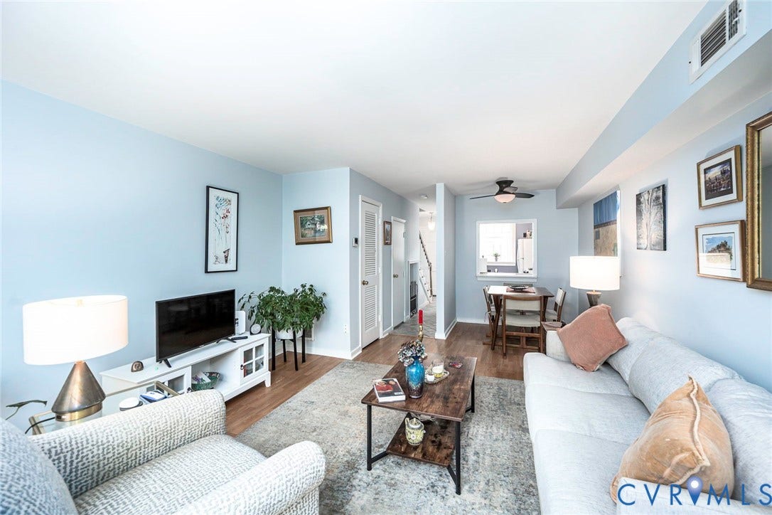 Open concept living and dining area with woodflooring, light blue walls, and a ceiling fan in the dining space