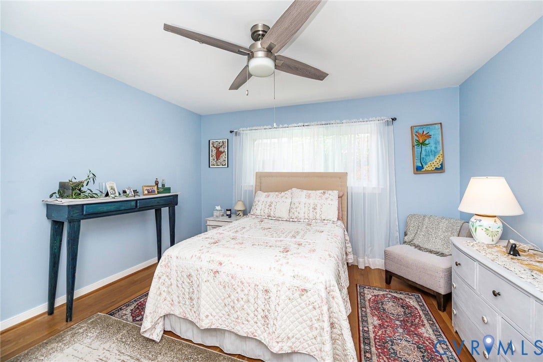 Primary bedroom with hardwood flooring, ceiling fan and calming paint color