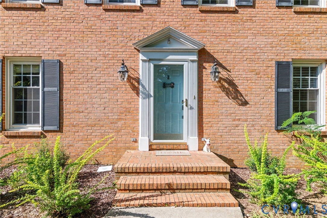Brick exterior with a light blue front door, white door trim, and dark shutters