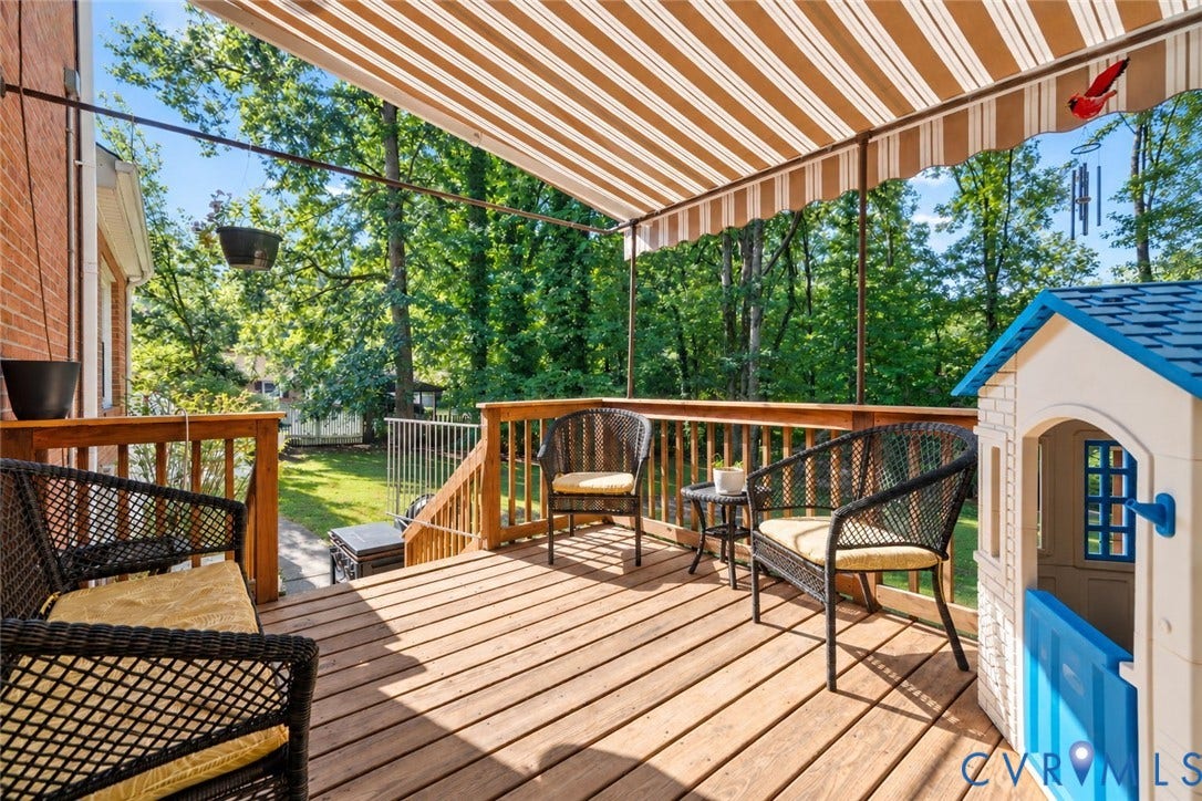 Expansive wood-finish deck with a striped retractable awning and wood railing