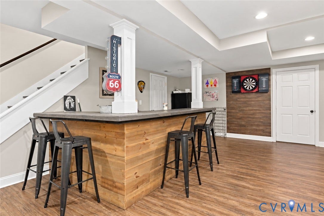 Wood-finish flooring, recessed lighting, built-in bar with wood paneling, white paneled doors, and white painted staircase