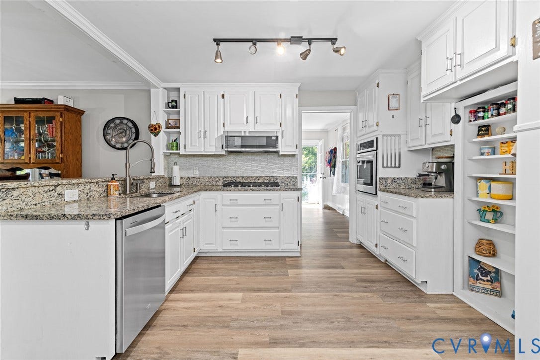 Kitchen featuring white cabinetry, granite countertops, stainless steel appliances, wood-finish flooring, and a subway tile backsplash