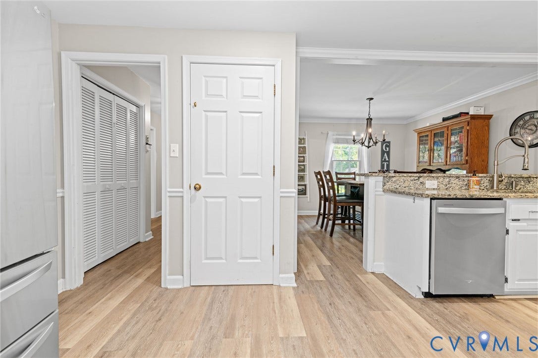 Light wood-finish flooring, white paneled doors, stainless steel dishwasher, and granite-style countertops
