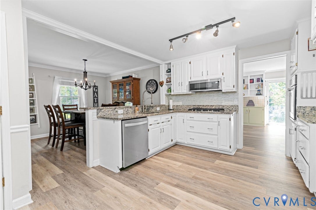 Kitchen featuring white cabinetry, stainless steel appliances, granite countertops, and wood-finish flooring