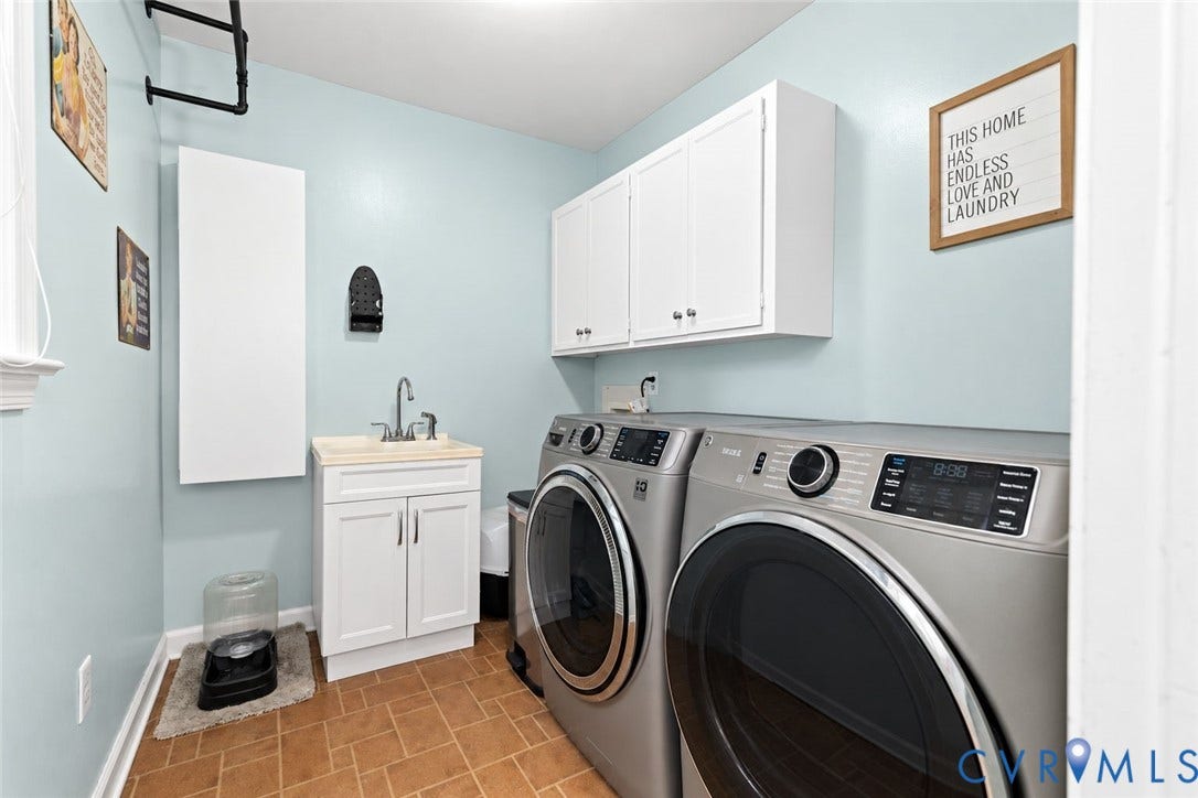 Utility room with tile flooring, white cabinetry, a sink with a chrome faucet, and a wall-mounted drying rack