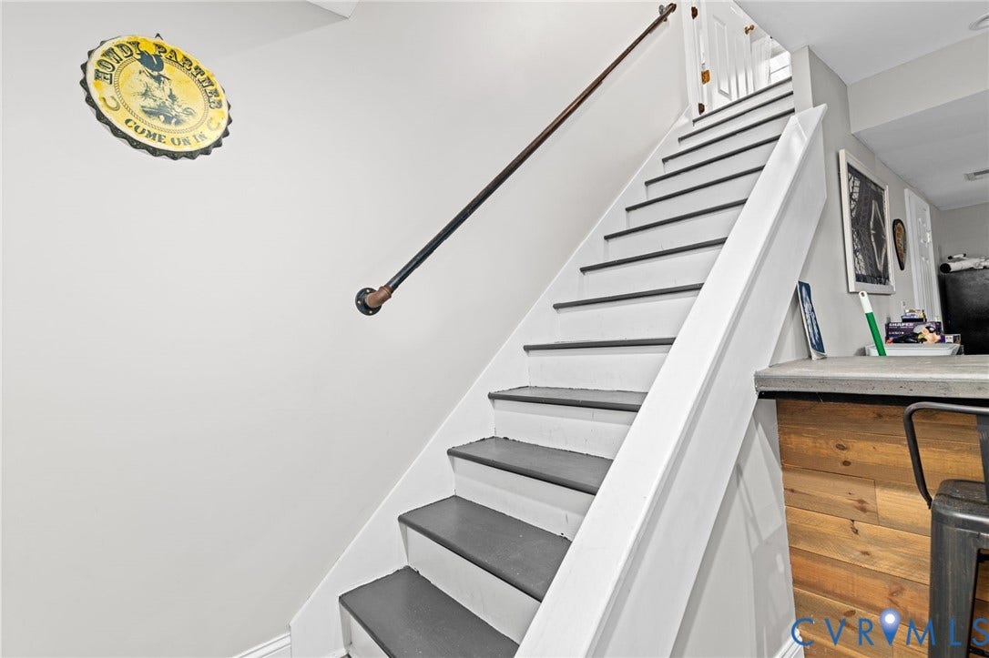Staircase with contrasting risers and treads, dark metal handrail, and white wall finishes