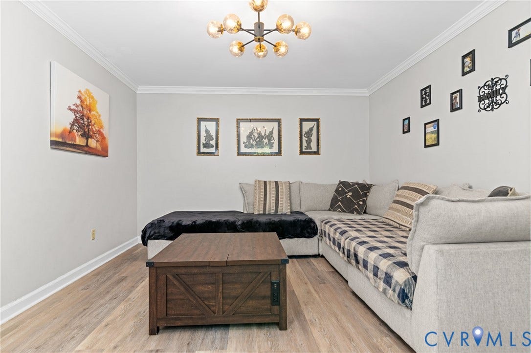 Wood-finish flooring, crown molding, and a contemporary ceiling fixture
