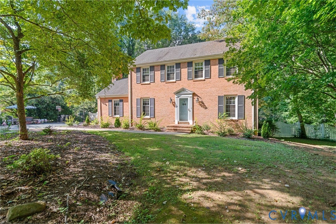 Brick exterior with dark shutters, symmetrical windows, and a portico entrance