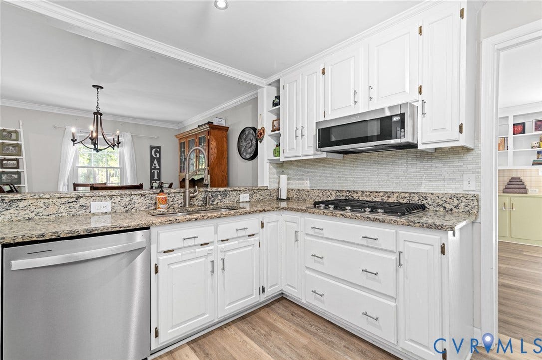 Kitchen featuring white cabinetry, granite countertops, stainless steel appliances, a built-in microwave, and wood-finish flooring