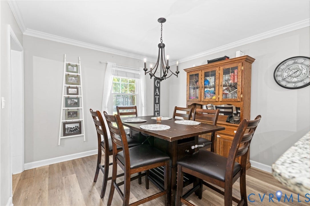Neutral wall paint with crown molding, wood-finish flooring, and a chandelier light fixture