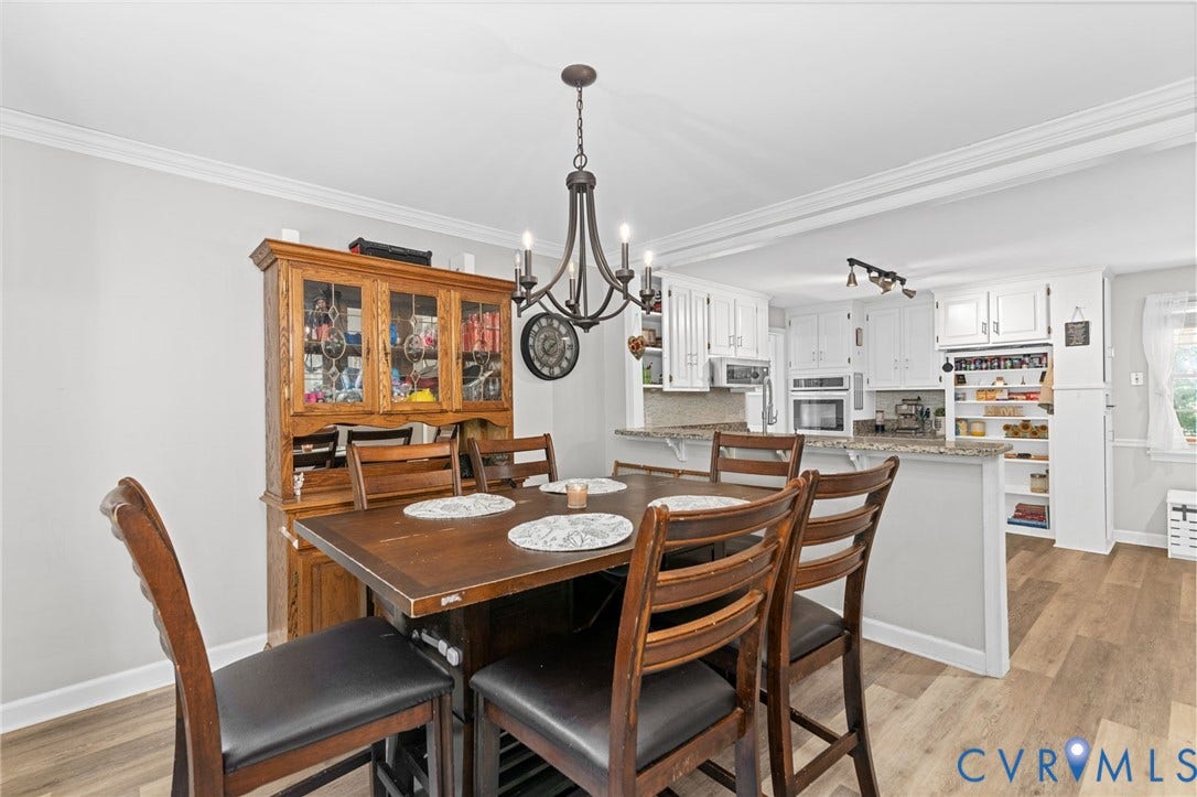 Wood-finish flooring, crown molding, white kitchen cabinetry, recessed lighting, and granite countertops