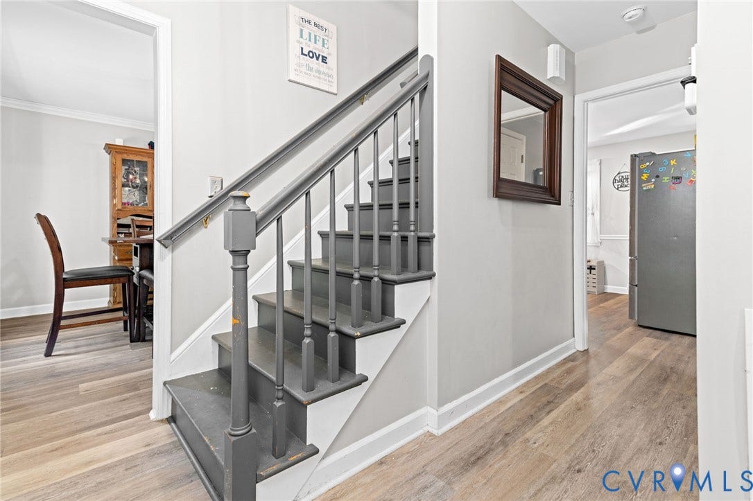 Staircase with painted banister and risers, complemented by wood-finish flooring and light gray wall tones