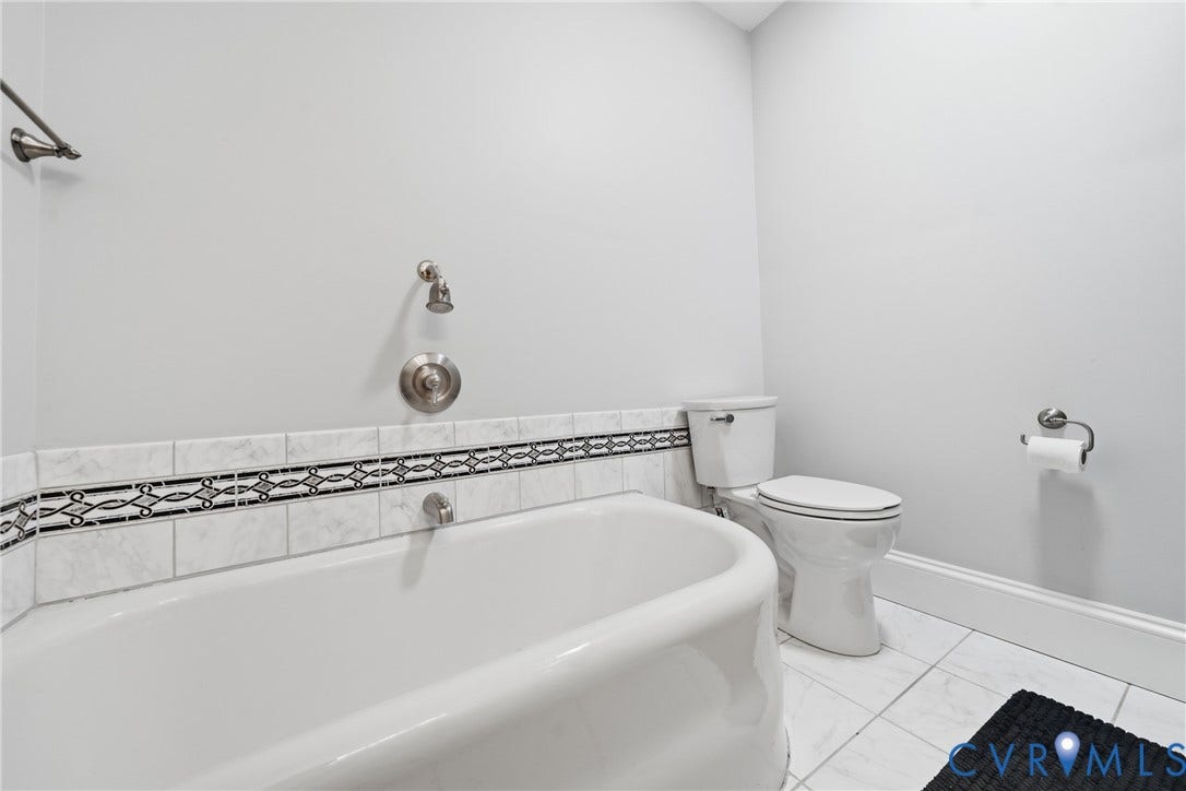 1500 Avondale Avenue, Bellevue, Richmond, VA 23227 White ceramic tile flooring, built-in bathtub, decorative tile accent band, white toilet, and brushed nickel fixtures