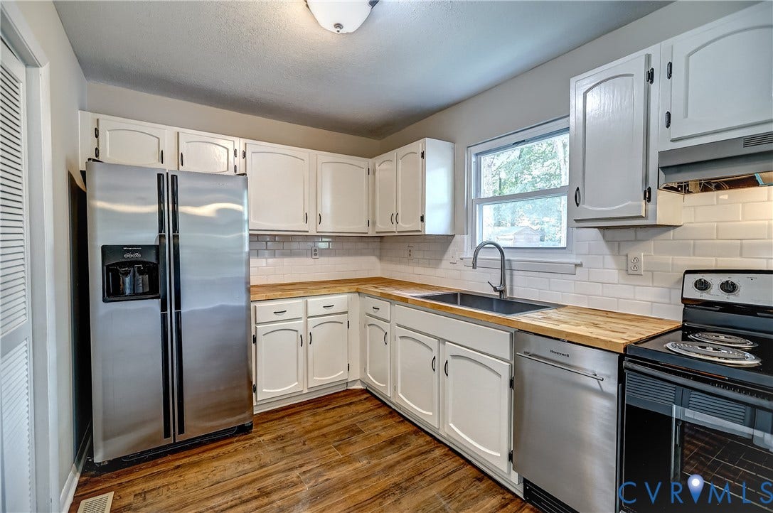 6100 Meadwood Circle, Hopkins Rd Corridor, Richmond, VA 23234 Kitchen featuring bright white cabinetry with modern hardware, butcher block countertops, brand new stainless steel appliances, a chic, subway tile backsplash, and wood-finish flooring