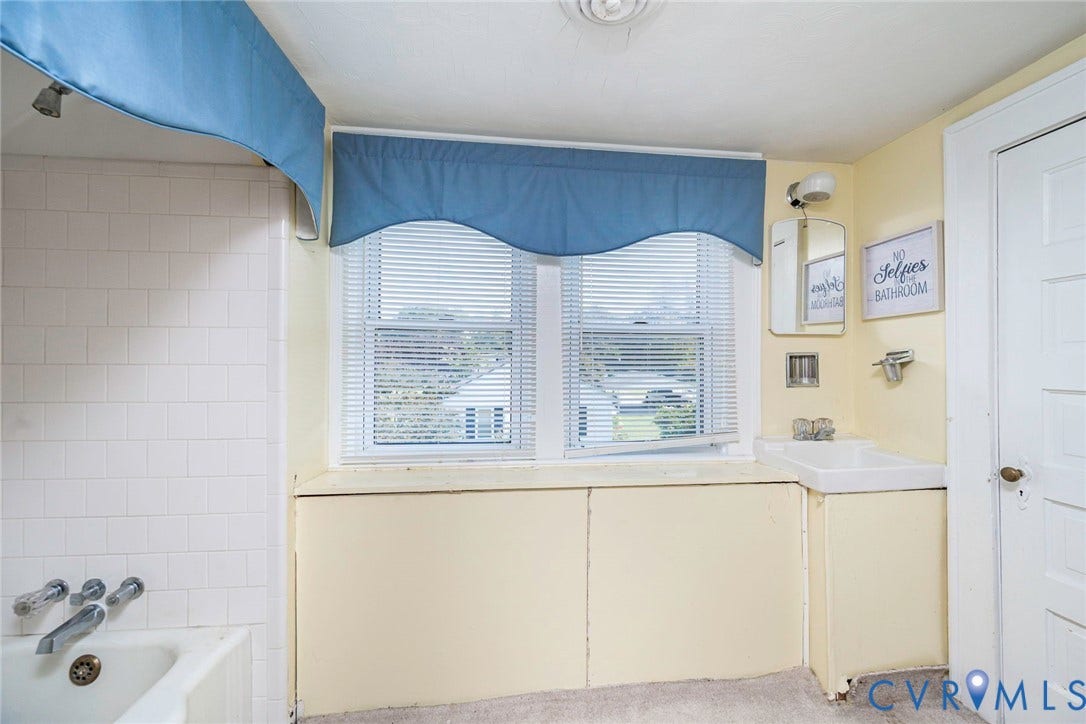 4912 Water View Road, Water View, Jamaica, VA 23180 White tiled shower surround, dual-pane window with blinds, wall-mounted sink, and a white interior door
