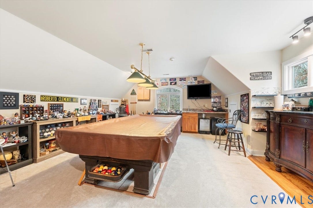 8908 Thomas Higgs Court, Toano, VA 23168 Sloped ceilings, wall-mounted track lighting, built-in wet bar, wood-finish flooring, and a window with arched transom