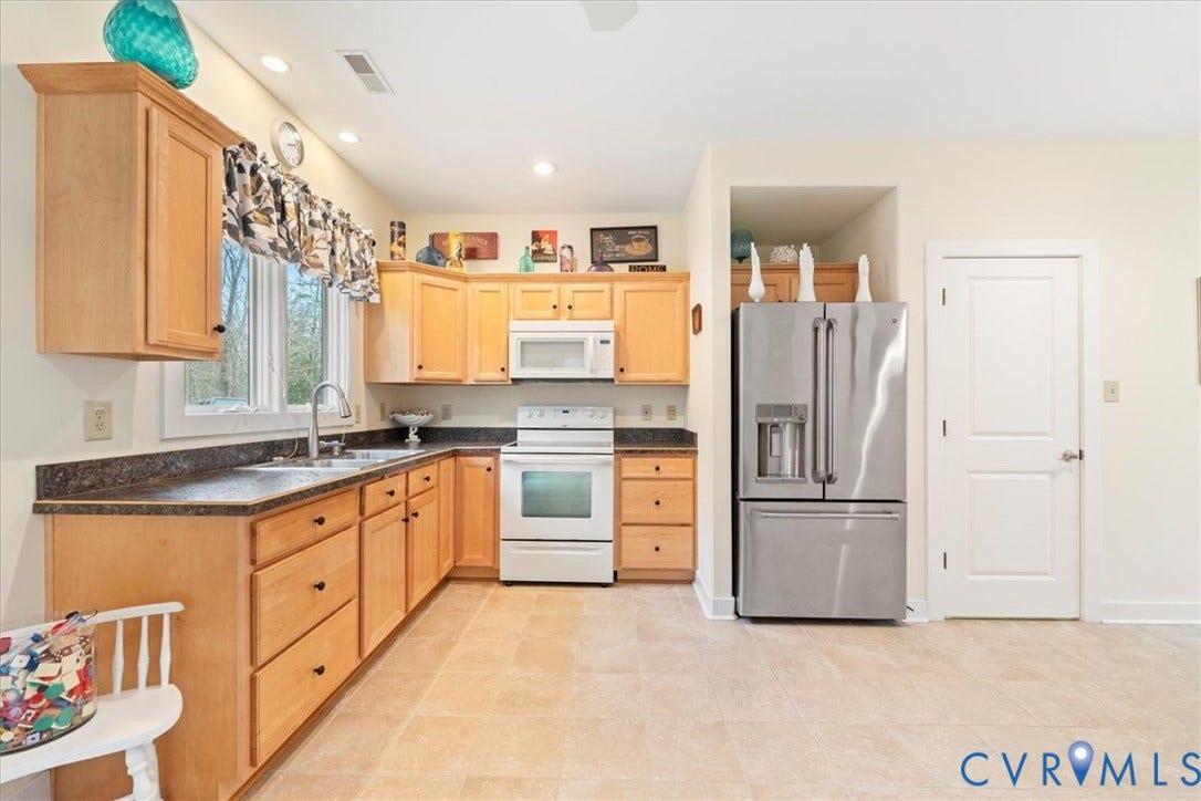 8908 Thomas Higgs Court, Toano, VA 23168 Kitchen featuring hardwood cabinetry, dark countertops, a double basin stainless steel sink, and stainless steel refrigerator