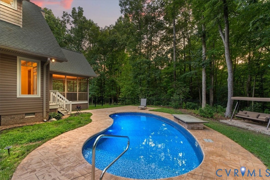 8908 Thomas Higgs Court, Toano, VA 23168 Freeform inground pool with an adjacent stamped concrete patio, screened porch, and mature trees surrounding the property