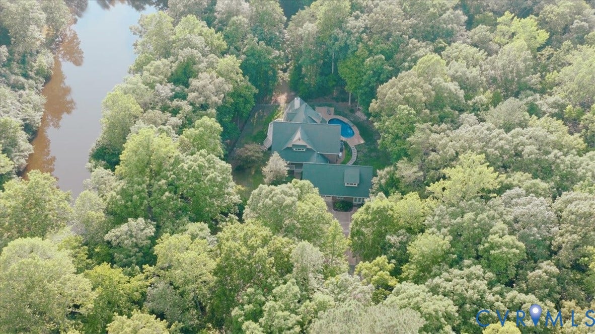 8908 Thomas Higgs Court, Toano, VA 23168 Spacious property surrounded by lush green trees, featuring a residence with a dark roof, an outdoor pool, and a private driveway