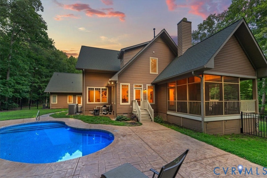 8908 Thomas Higgs Court, Toano, VA 23168 Rear exterior with a freeform swimming pool, stamped concrete patio, screened porch, and mature trees
