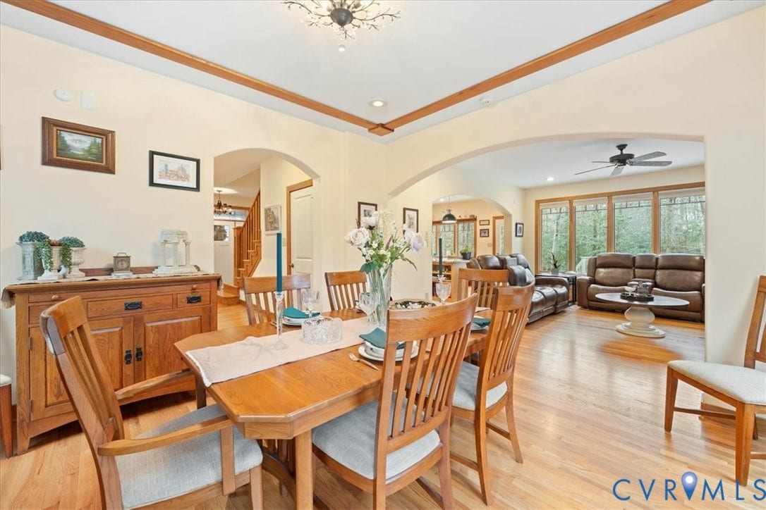8908 Thomas Higgs Court, Toano, VA 23168 Archways connecting spaces, chandelier lighting, hardwood flooring, wall-mounted artwork, and a built-in wooden sideboard