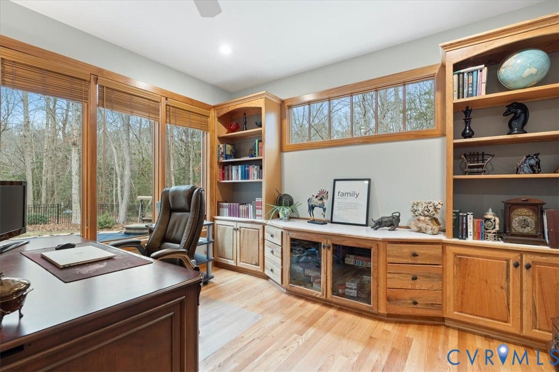 8908 Thomas Higgs Court, Toano, VA 23168 Expansive windows with natural hardwood frames, custom built-in cabinetry, integrated bookshelves, wood-finish flooring, and a recessed ceiling light fixture