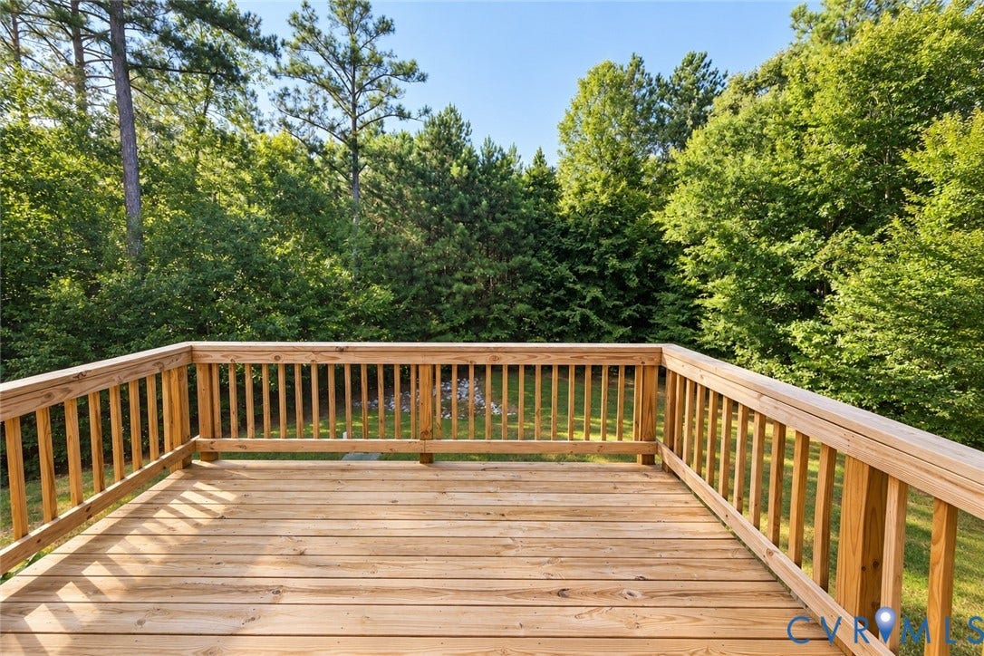 Expansive wood deck with natural wood railings, overlooking a verdant tree line