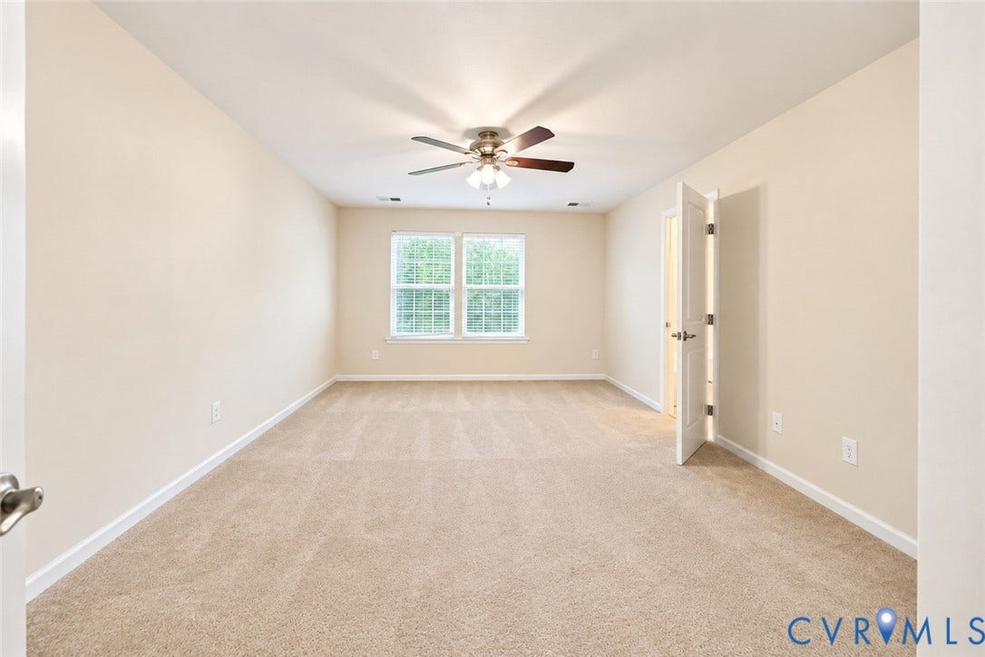 Neutral tone wall paint, carpet flooring, ceiling fan with integrated lighting, and white trim work