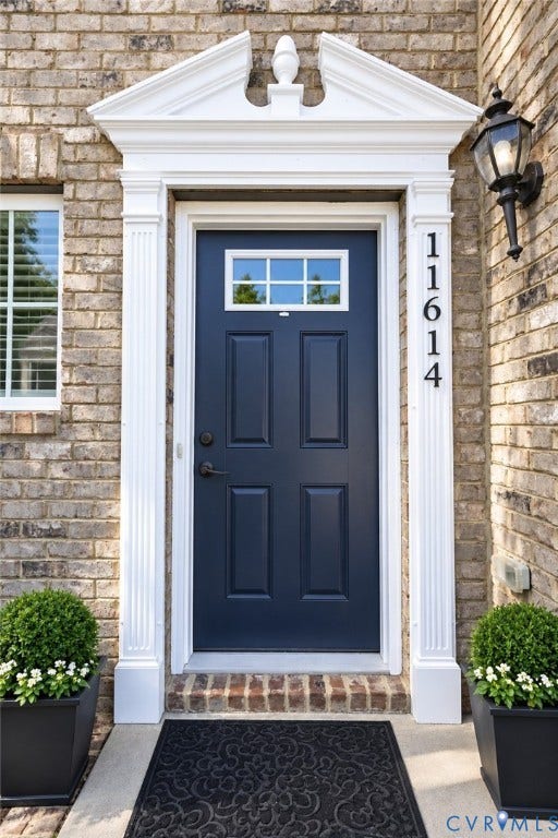 Brick exterior with a paneled entry door, transom window, and decorative door surround