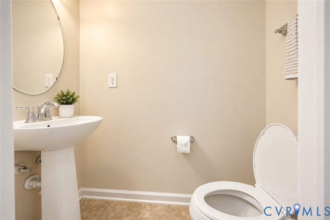 1st floor half-bath with Pedestal sink, wall-mounted mirror, two-handle chrome faucet, toilet, and tile flooring