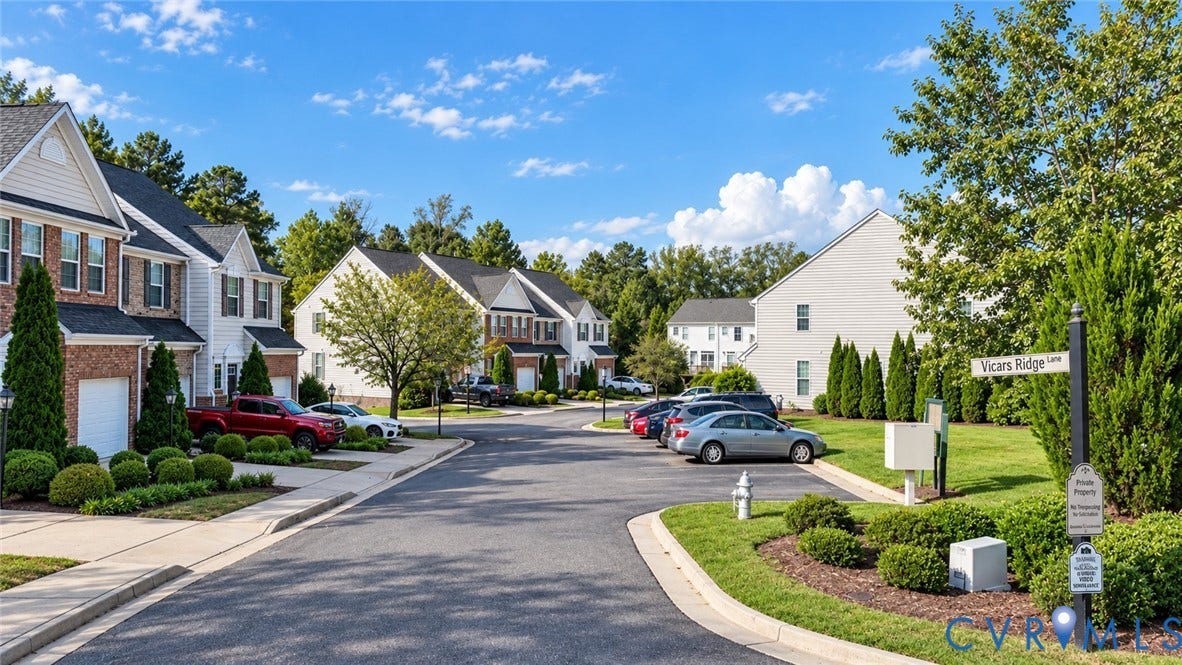 Street with residential properties featuring brick and siding exteriors, attached garages, and landscaped front yards