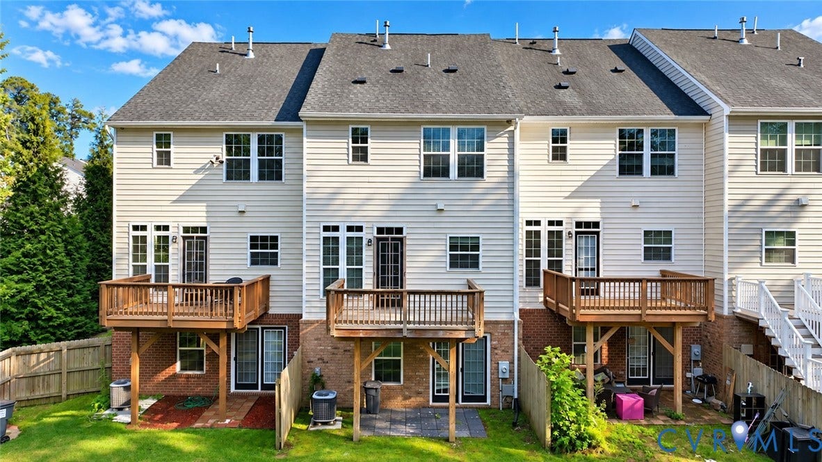 Rear exterior featuring wood decks, brick accents, and a fenced backyard