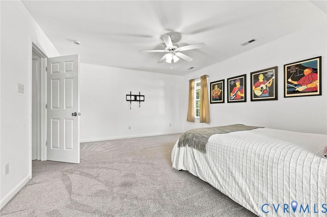 11342 McCauliff Court, North Chesterfield, VA 23236 Spacious bedroom #2 Textured gray carpeting, white painted walls, ceiling fan, natural light window, and a wall-mounted bracket