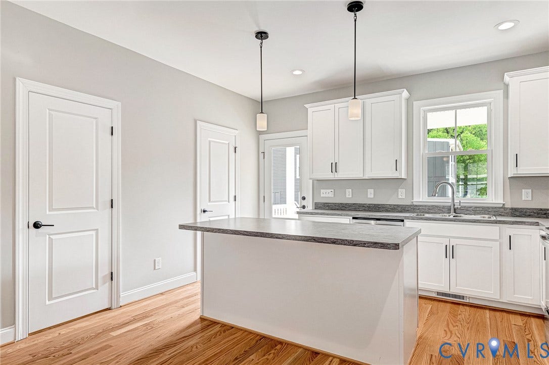 310 E 33rd Street, Swansboro West, Richmond, VA 23224 Kitchen with wood-finish flooring, white cabinetry, a center island with countertop seating, recessed lighting, and pendant lighting fixtures