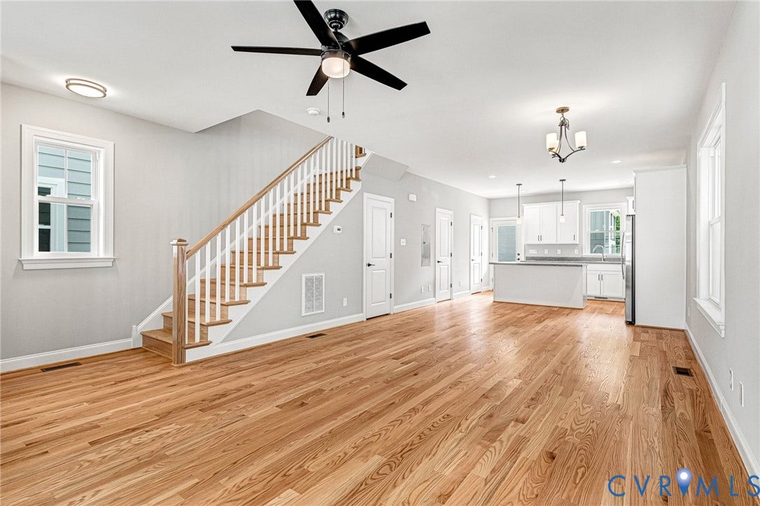 310 E 33rd Street, Swansboro West, Richmond, VA 23224 Open-concept interior featuring wood-finish flooring, a white-spindled staircase with wood handrails, and a contemporary kitchen with white cabinetry and an island