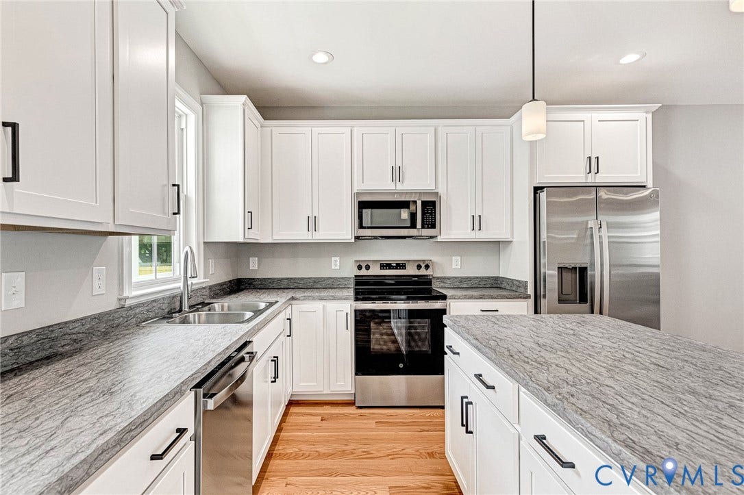 310 E 33rd Street, Swansboro West, Richmond, VA 23224 White cabinetry with matte black hardware, stainless steel appliances, light gray patterned countertops, dual basin sink, and wood-finish flooring