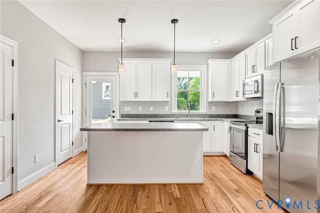 310 E 33rd Street, Swansboro West, Richmond, VA 23224 White cabinetry, stainless steel appliances, wood-finish flooring, island with countertop, and pendant lighting