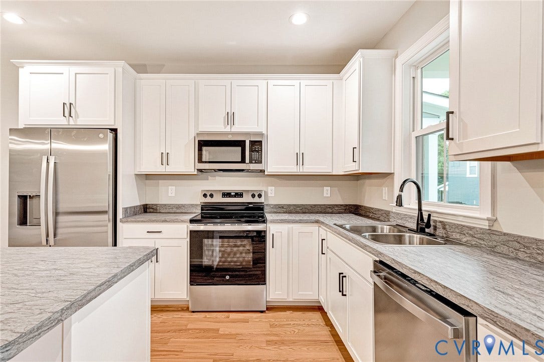 308 E 33rd Street, Swansboro West, Richmond, VA 23224 Modern kitchen featuring white shaker cabinetry, stainless steel appliances, grey stone-patterned countertops, wood-finish flooring, and a double basin sink with a matte black faucet