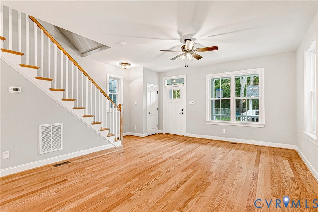 308 E 33rd Street, Swansboro West, Richmond, VA 23224 Hardwood flooring, painted white staircase with wood-finish handrail, white trim, ceiling fan with light fixture, and multiple windows