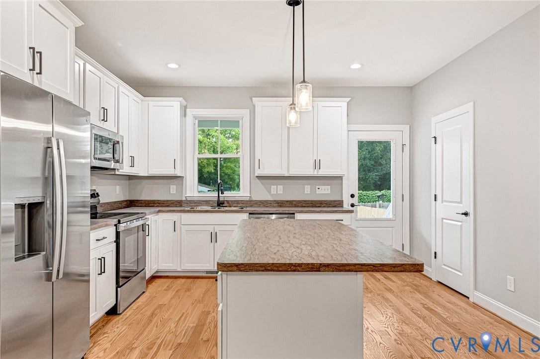 308 E 33rd Street, Swansboro West, Richmond, VA 23224 White cabinetry with matte black hardware, stainless steel appliances, wood-finish flooring, and a center island with pendant lighting