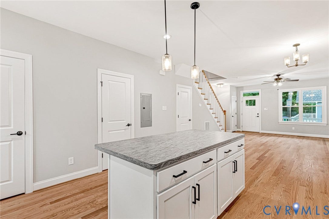 308 E 33rd Street, Swansboro West, Richmond, VA 23224 Kitchen island with stone-finish countertop, pendant lighting, hardwood-finish flooring, staircase with wood handrail, and white paneled doors