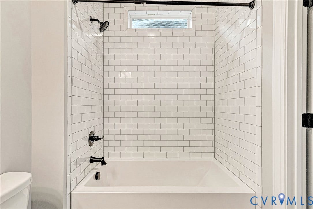 308 E 33rd Street, Swansboro West, Richmond, VA 23224 Bathtub with white subway tile surround, matte black fixtures, and an upper transom window