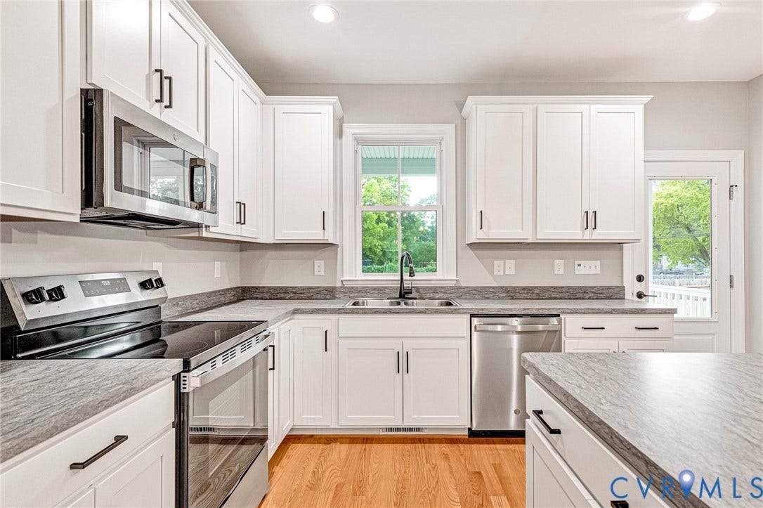 308 E 33rd Street, Swansboro West, Richmond, VA 23224 Kitchen featuring white cabinetry, light-toned countertops, stainless steel appliances, and wood-finish flooring
