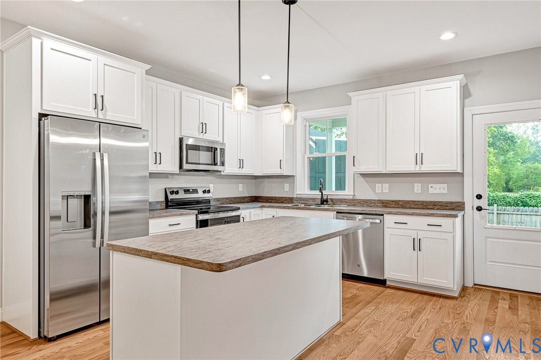 308 E 33rd Street, Swansboro West, Richmond, VA 23224 Kitchen featuring white shaker cabinetry, stainless steel appliances, a center island, pendant lighting, and wood-finish flooring